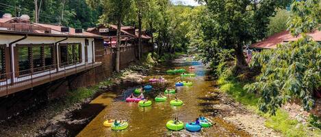 A river with people on inflatable tubes, a bridge, and buildings on the banks.