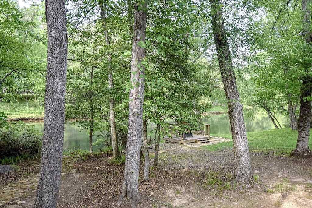 A forested area with a wooden deck by a lake.
