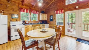 Una cabaña de madera con cocina equipada, que incluye estufa, refrigerador y mesa de comedor con sillas.