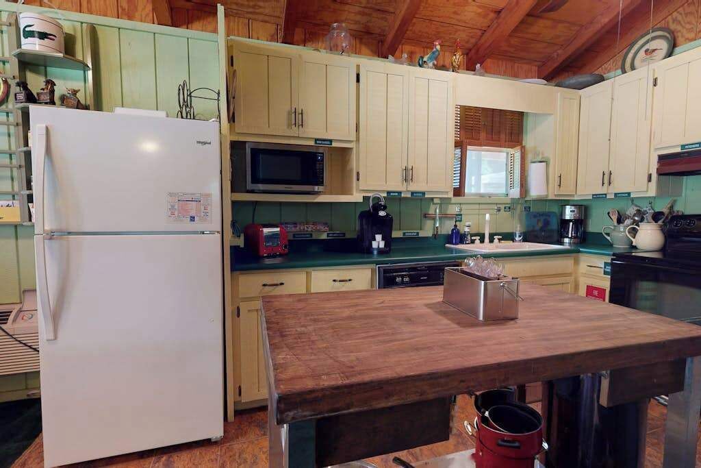 A compact kitchen with a refrigerator, microwave, and wooden table.
