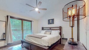 Ein Schlafzimmer mit einem Bett, einem Deckenventilator, einem Fenster mit Vorhängen und einer Stehlampe.