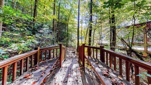 A wooden pathway leading through a forest with a wooden railing on both sides. - Indian Rock Lake Cabin (Cherry Log)