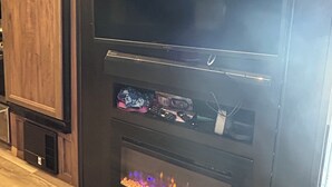 Eine Küche mit Holzschränken, einer schwarzen Dunstabzugshaube und einem eingebauten Kamin mit Feuer.