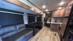 Ein kompaktes Wohnmobil-Interieur mit einer Sitzecke, einer Küchenzeile und Holzböden.