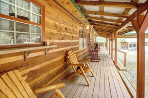 Eine Holzhütte mit Veranda, Holzbanken und Blick auf die umliegende Landschaft.