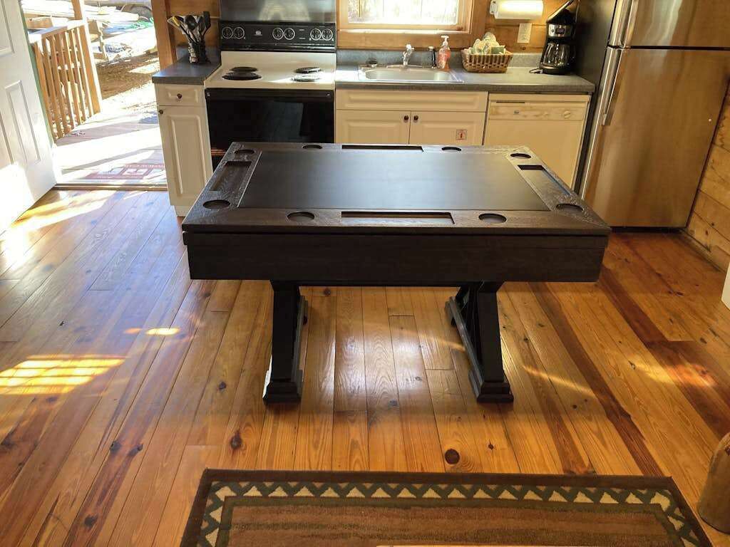 A kitchen with a wooden floor, a stove, a sink, and a refrigerator.