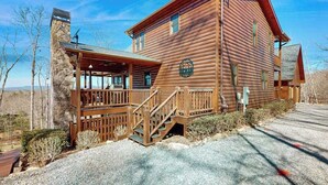 A log cabin with a stone chimney, wooden deck, and a covered porch. - Bougie Bear Cabin Stay (Morganton)