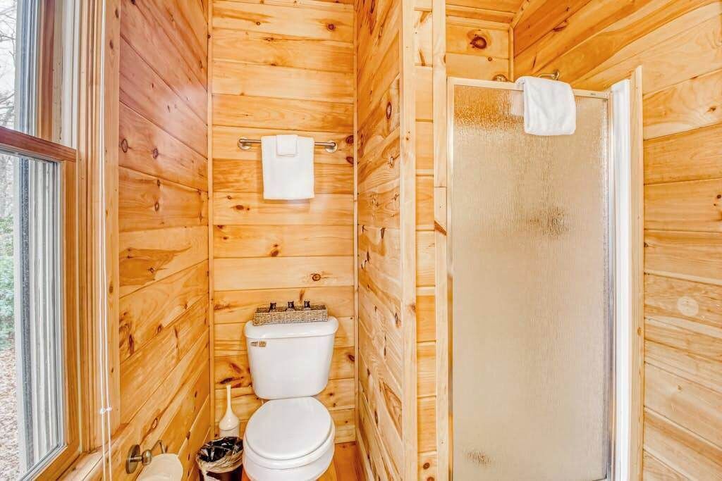 Et badeværelse i en træhytte med toilet, vask og en glasbruger.