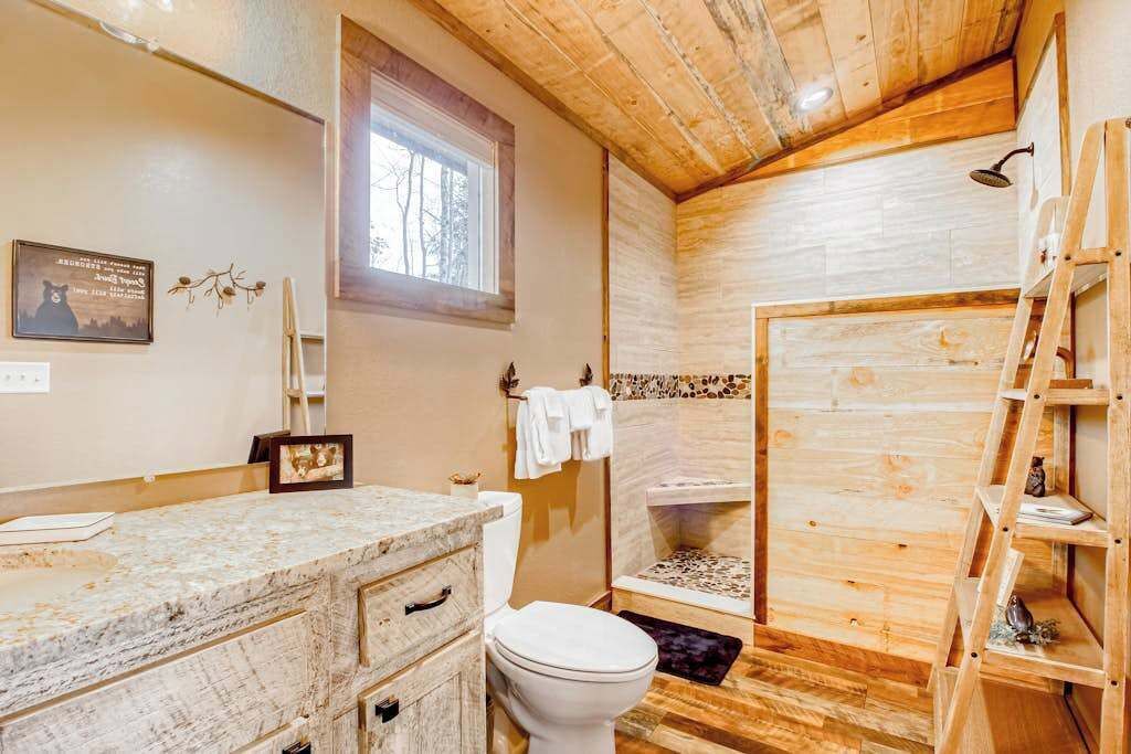 Interno in legno con bagno dotato di toilette, lavandino e zona doccia.