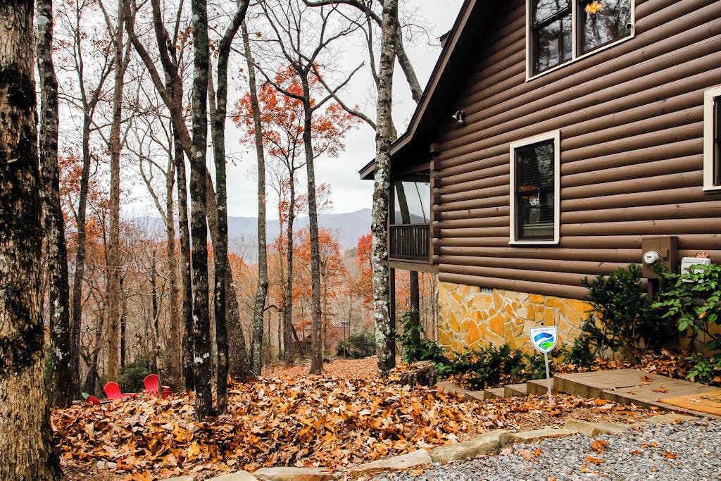 Une cabane en rondins avec des fondations en pierre, un balcon et une vue sur une zone boisée.