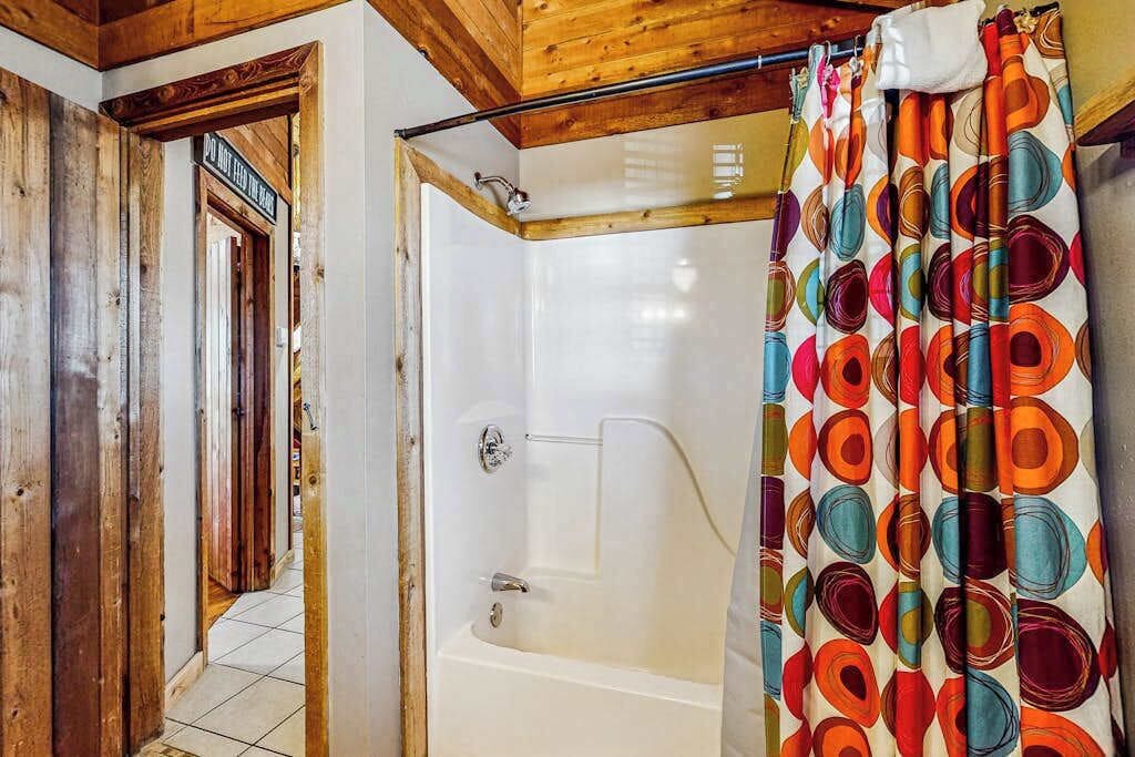 A bathroom with a shower, a bathtub, and a wooden ceiling.