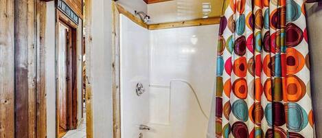 A bathroom with a shower, a bathtub, and a wooden ceiling.