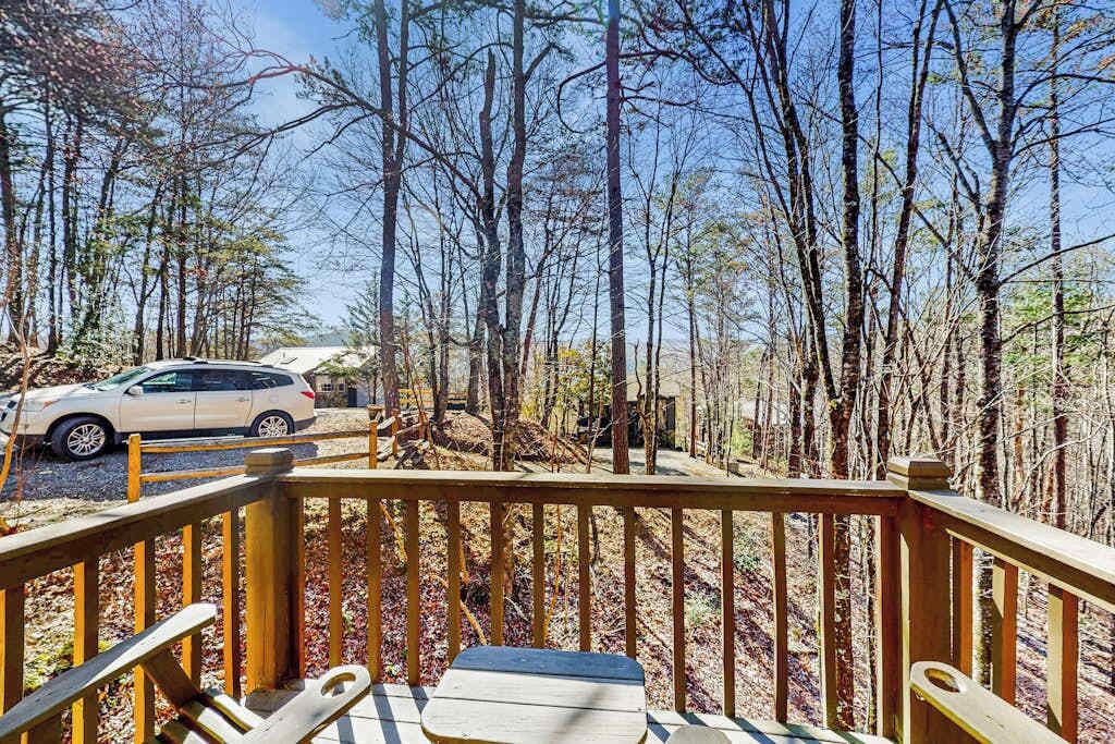 Une terrasse en bois offrant une vue sur une forêt et une voiture garée.
