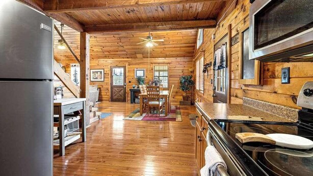 L’intérieur d’une cabane en rondins comprend une cuisine, un coin repas et un escalier menant à une mezzanine.