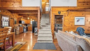 L’intérieur d’une cabane en bois comprend un escalier, une cuisine, un coin repas et un salon.