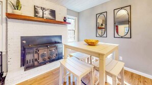 Une cuisine moderne dotée d’une cuisinière intégrée, de murs en briques blanches, de planchers en bois et d’un coin repas avec une table et des bancs.