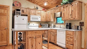 A kitchen with wooden cabinets, a white refrigerator, a microwave, a stove, and a dishwasher. - Bear Necessity Cabin (Hiawassee)