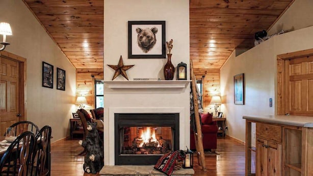 A fireplace with a bear decoration, a star, and a framed animal head on the mantel. - Bear Necessity Cabin (Hiawassee)