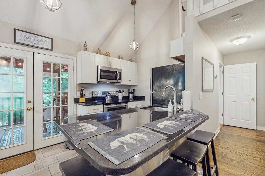 A kitchen with a central island, white cabinets, a microwave, and a stainless steel sink.
