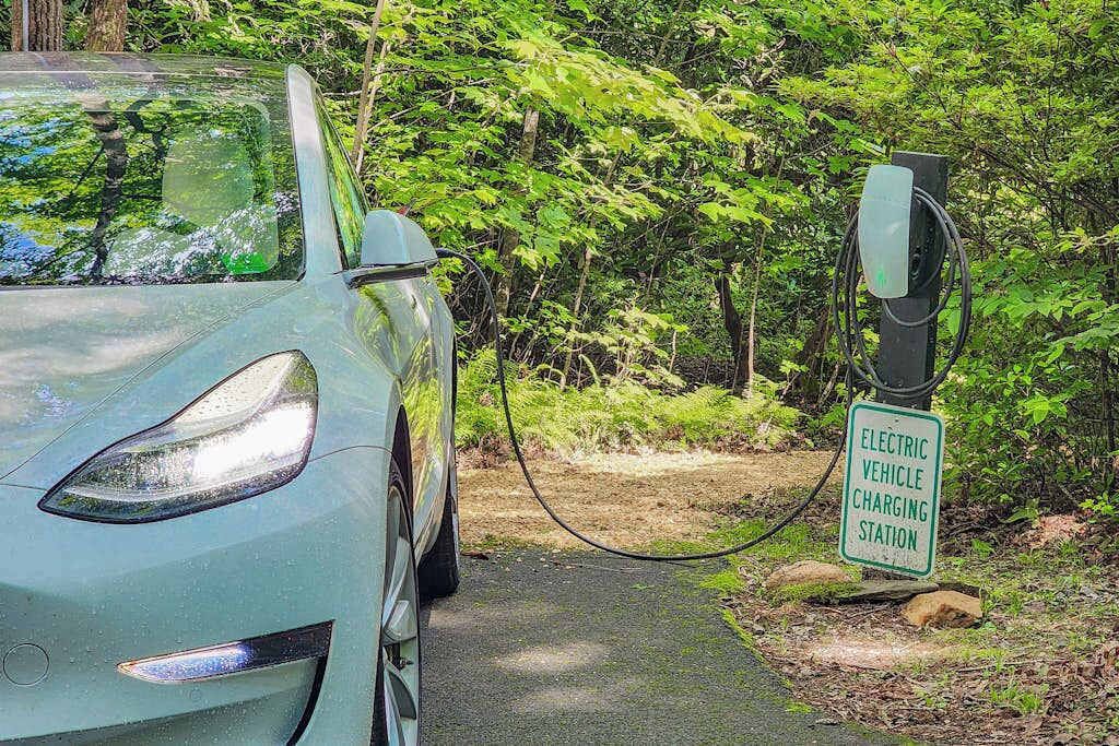 A car parked at an electric vehicle charging station in a wooded area.