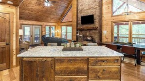 Una cocina amplia con una isla grande, techo de madera y chimenea de piedra.