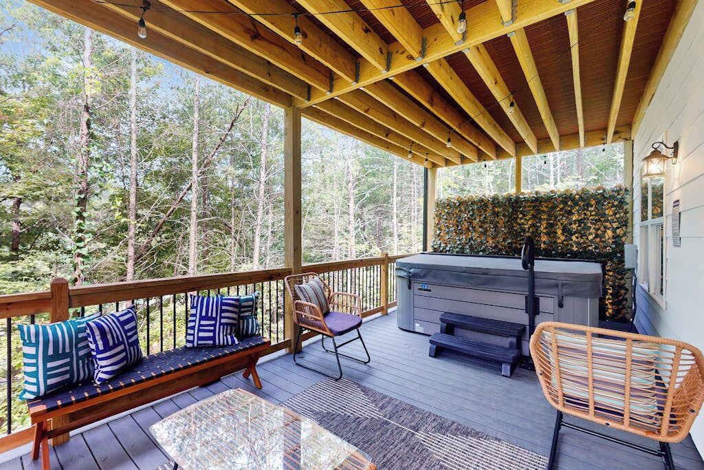 Une terrasse extérieure couverte, dotée d’un banc en bois, de sièges et d’un jacuzzi.