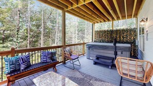 Terraza exterior techada con un banco de madera, asientos y un jacuzzi.
