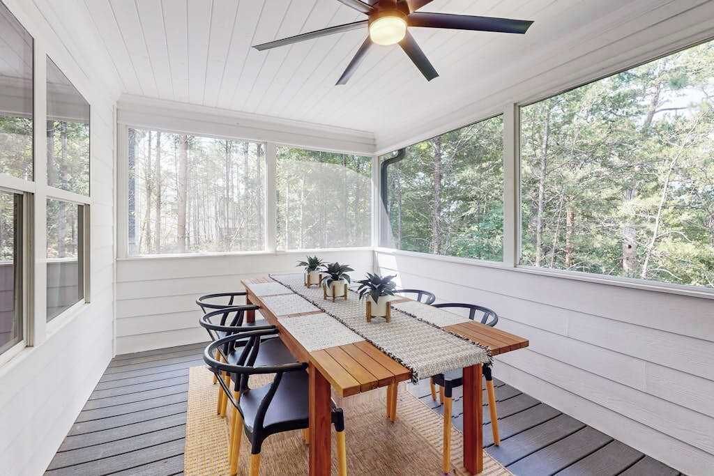 Un espace repas abrité, équipé d’une table, de chaises et d’un ventilateur de plafond.