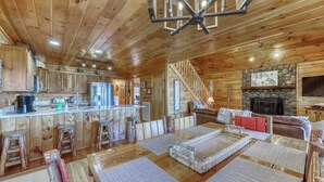 A wooden cabin interior with a kitchen, dining area, and living room. - Dogwood Overlook Cabin (Mineral Bluff)