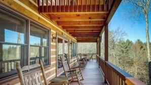 A wooden porch with rocking chairs and a view of trees. - Dogwood Overlook Cabin (Mineral Bluff)