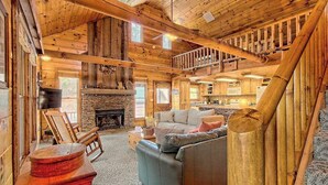 A log cabin interior with a stone fireplace, a sofa, and a staircase. - Best Kept Secret Stay (Blue Ridge)