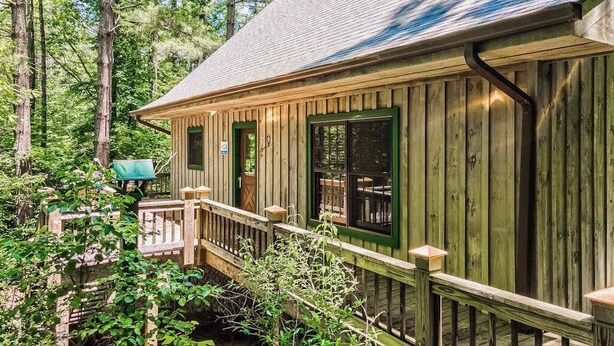 A wooden cabin with a deck, surrounded by trees. - Osprey Landing Retreat (Clarkesville)
