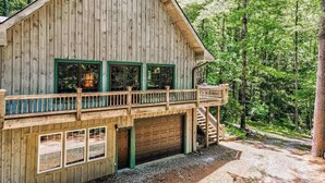 A wooden cabin with a balcony, a garage, and a staircase leading to the upper level. - Osprey Landing Retreat (Clarkesville)