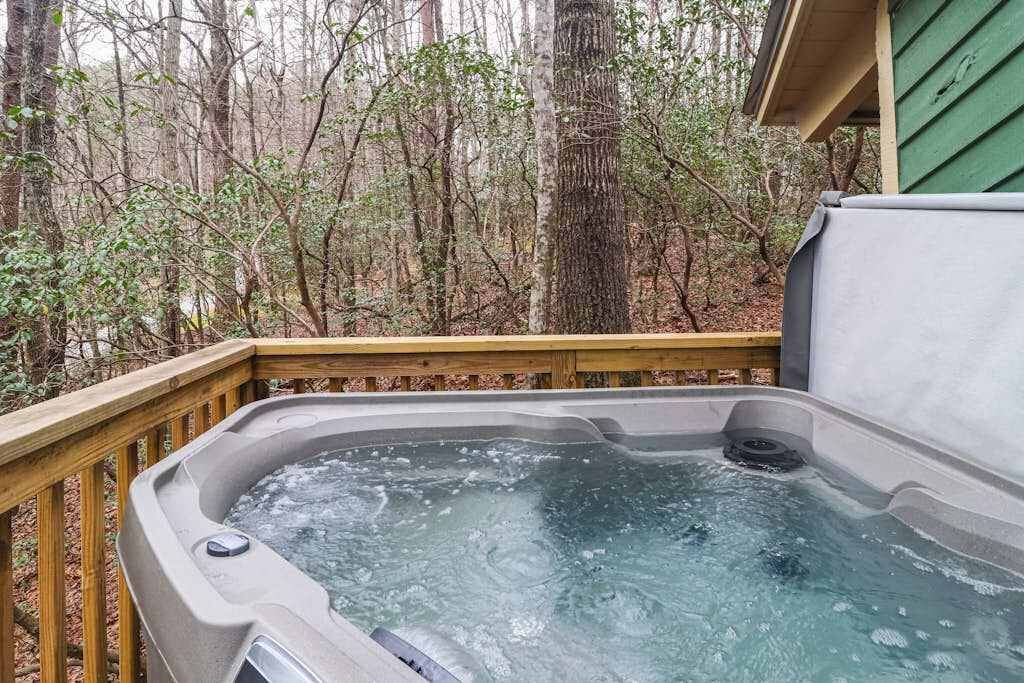 Un bain à remous sur une terrasse en bois, avec une forêt en arrière-plan.