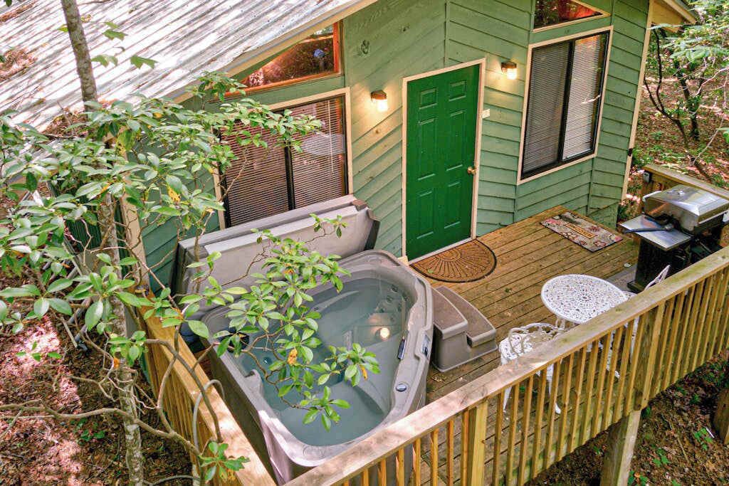 A hot tub on a wooden deck, a green door, and a small outdoor seating area.