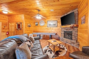 A log cabin interior with a leather sofa, a pool table, a fireplace, and a mounted TV. - Red Oak Luxe Mountain Cabin (Blue Ridge)