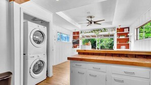 A laundry area with stacked washers and dryers, a wooden countertop, and a ceiling fan. - EnDeering Retreat Stay (Atlanta)