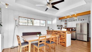 A modern kitchen with white cabinets, a wooden dining table, and a built-in island. - EnDeering Retreat Stay (Atlanta)