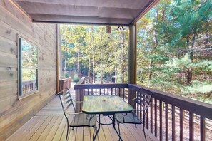 Une terrasse en bois avec une table et des chaises, donnant sur une zone boisée.