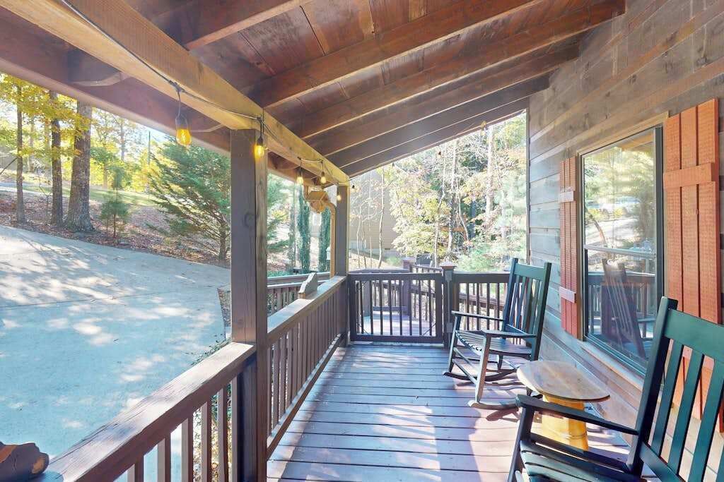A wooden deck with a railing, a table, and two chairs.