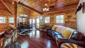 L’intérieur d’un chalet en bois comprend un coin repas, un canapé et une statue de chien.