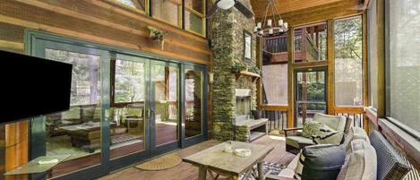 A spacious interior with a stone pillar, a ceiling fan, and a large window overlooking a deck.