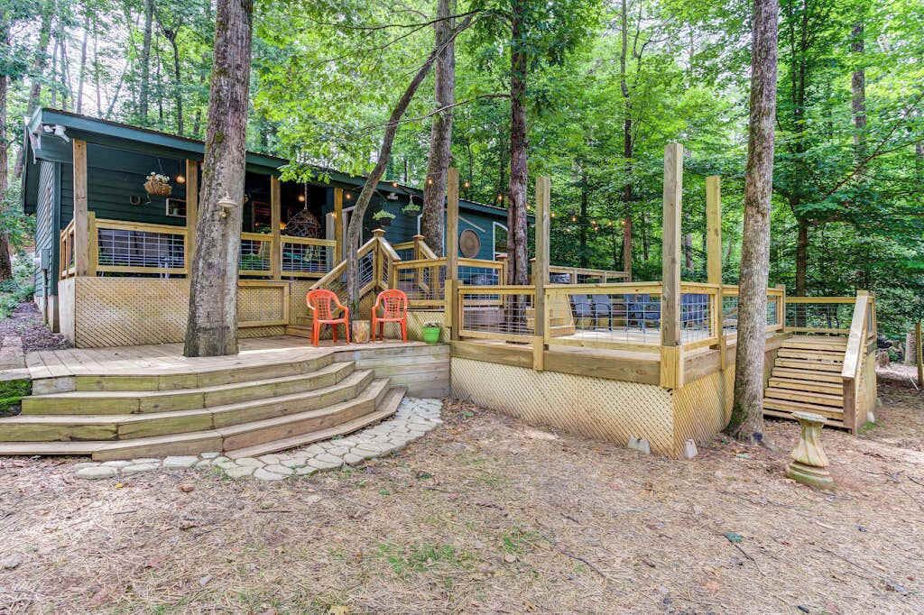 A wooden deck with steps leading to a building surrounded by trees.