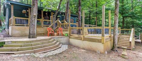 A wooden deck with steps leading to a building surrounded by trees.