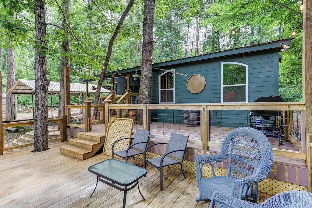 A wooden deck with chairs and a table, surrounded by trees.