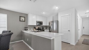 Una cocina moderna con armarios blancos, un refrigerador de acero inoxidable y un microondas.