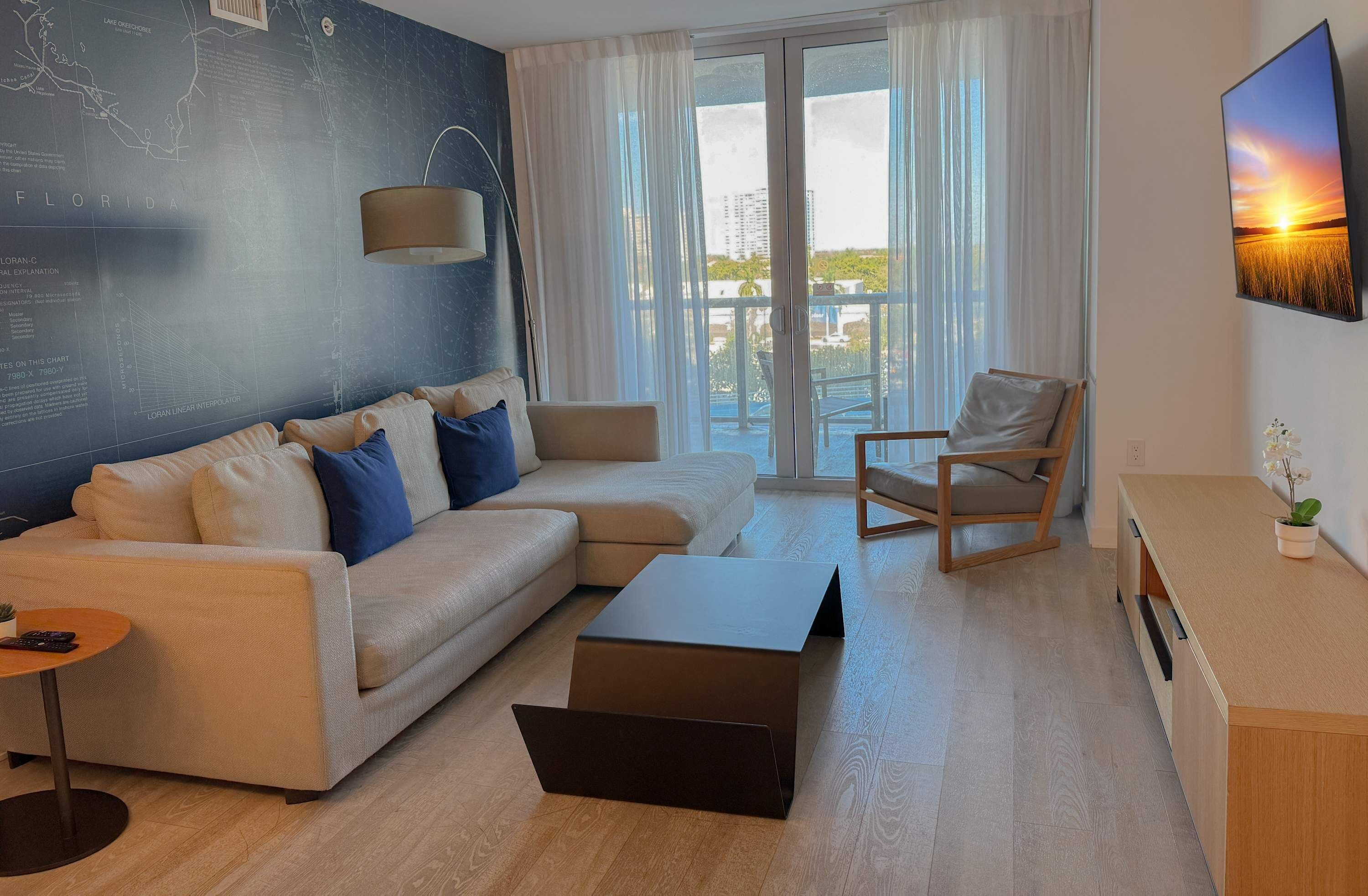 A modern living room with a sofa, a coffee table, a chair, and a large window with curtains.