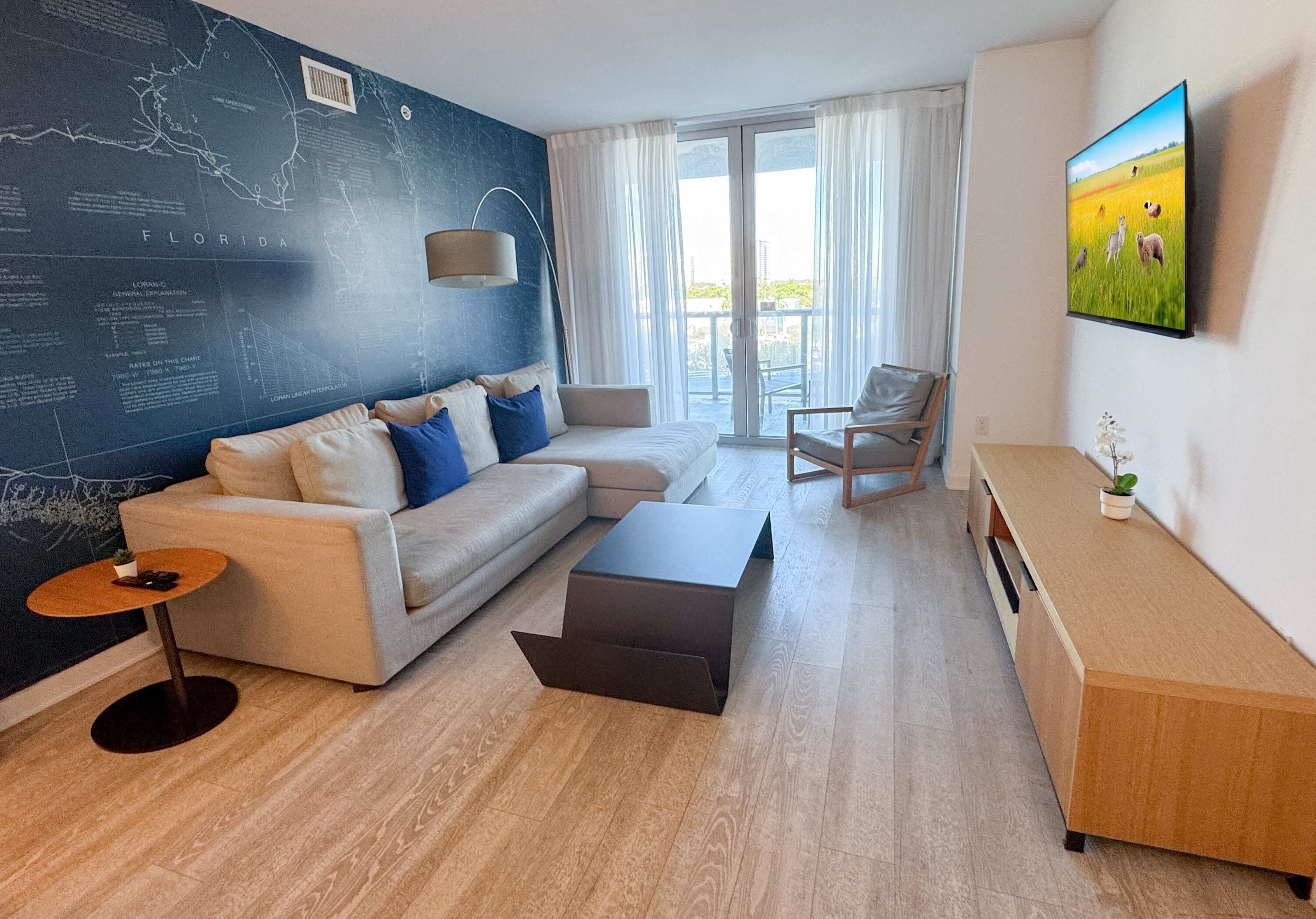 Una sala de estar moderna con un sofá modular, una mesa de centro, una mesita auxiliar, una silla y un televisor montado en la pared.