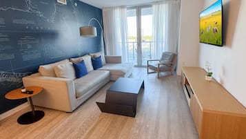 Una sala de estar moderna con un sofá modular, una mesa de centro, una mesita auxiliar, una silla y un televisor montado en la pared.