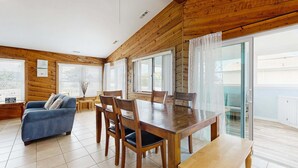 Un intérieur en bois comprenant une table à manger, des chaises, un canapé et un balcon avec vue.